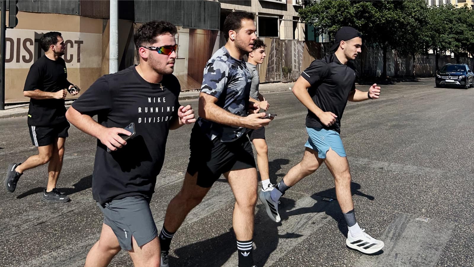 Four Run Club Beirut runners mid-stride down a sunlit Beirut street, the group in full