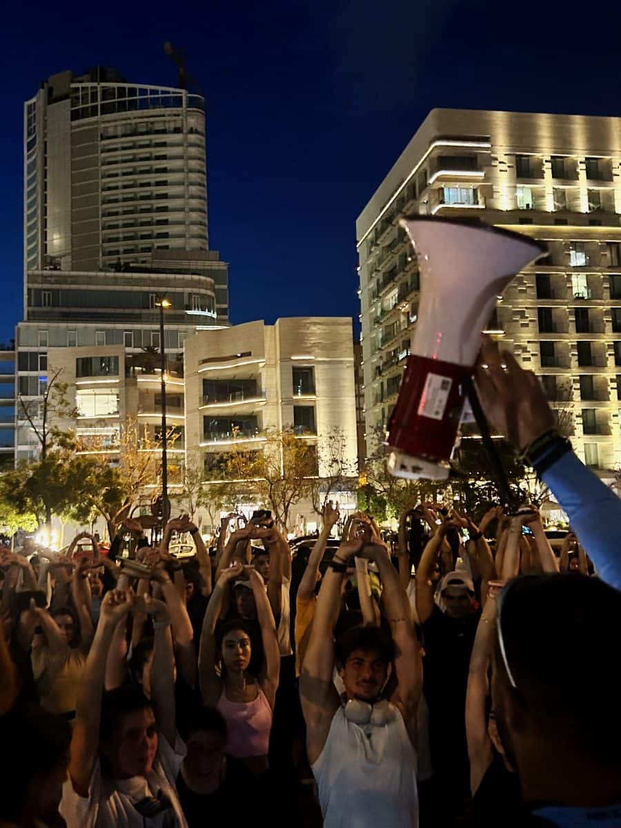 Hands in the air in a Run Club Beirut crowd at blue hour as a session is called to start