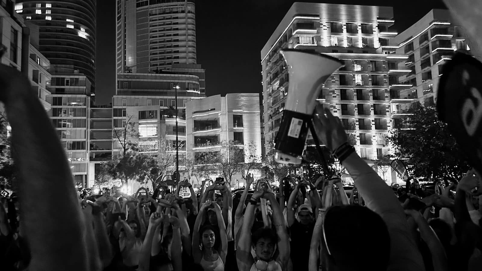 Hands in the air in a night crowd as a run is called to start over a megaphone