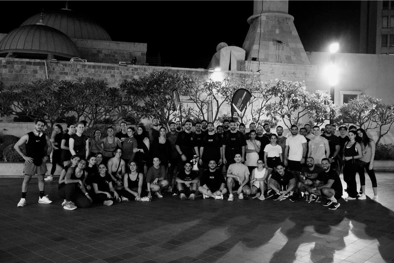 A wide Run Club Beirut group photographed at night in front of the city, most of the club in frame
