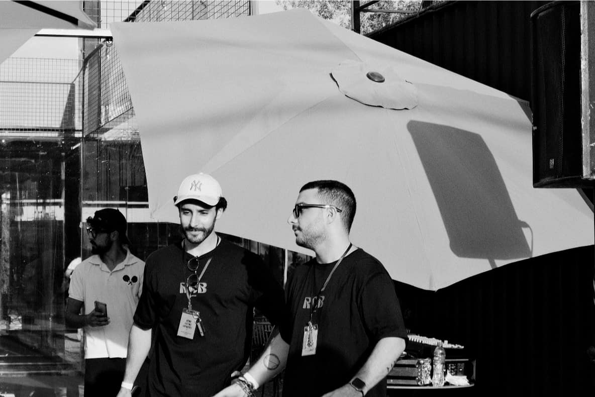 Two members talking beside the decks and a parasol after a run, the session still going